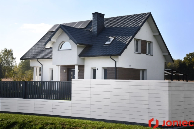Moderner Lamellenzaun in Weiß vor stilvollem Einfamilienhaus mit dunklem Dach