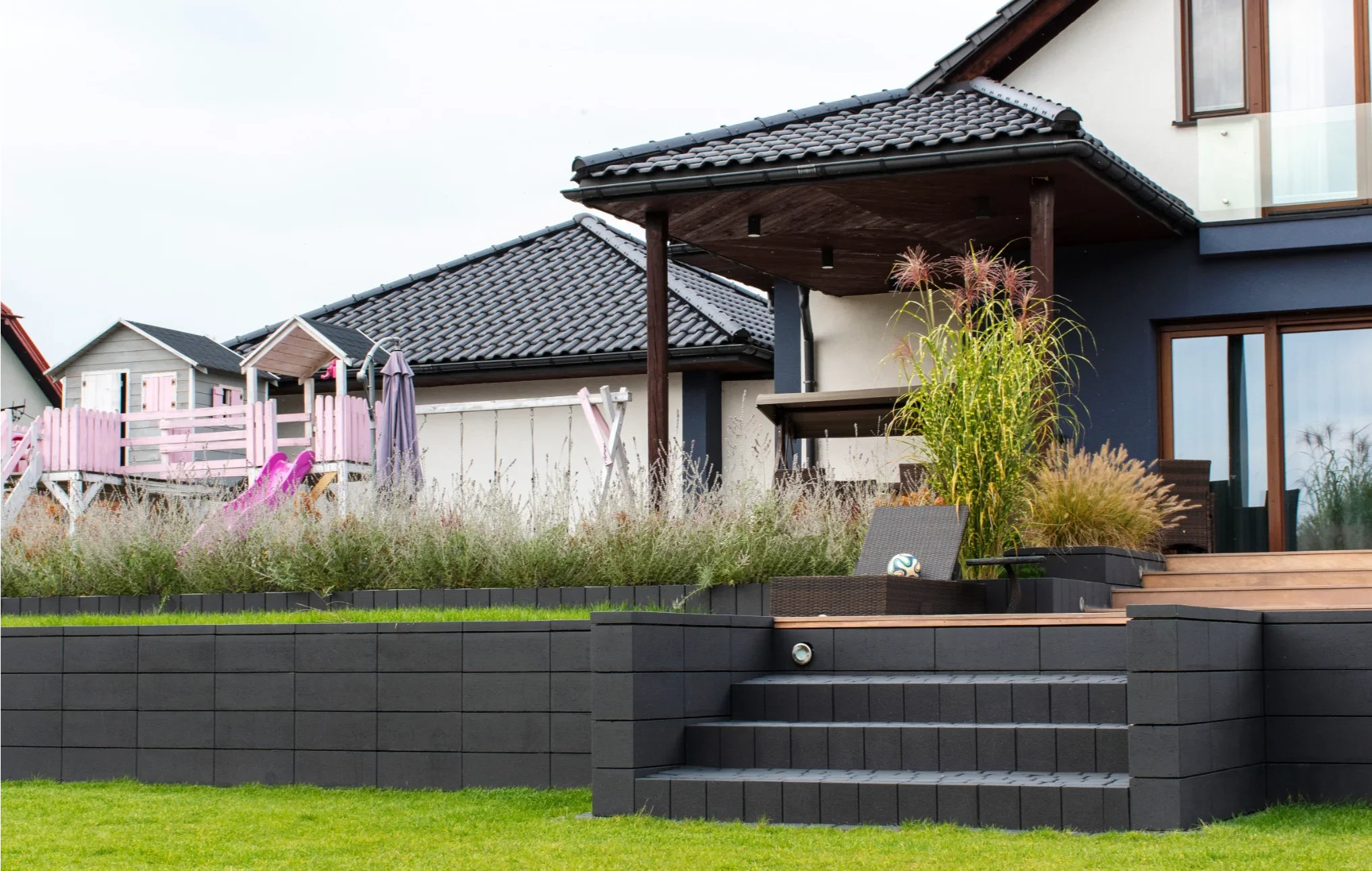 Terrassenüberdachung an Einfamilienhaus mit gestuften Pflanz- und Sitzbereich