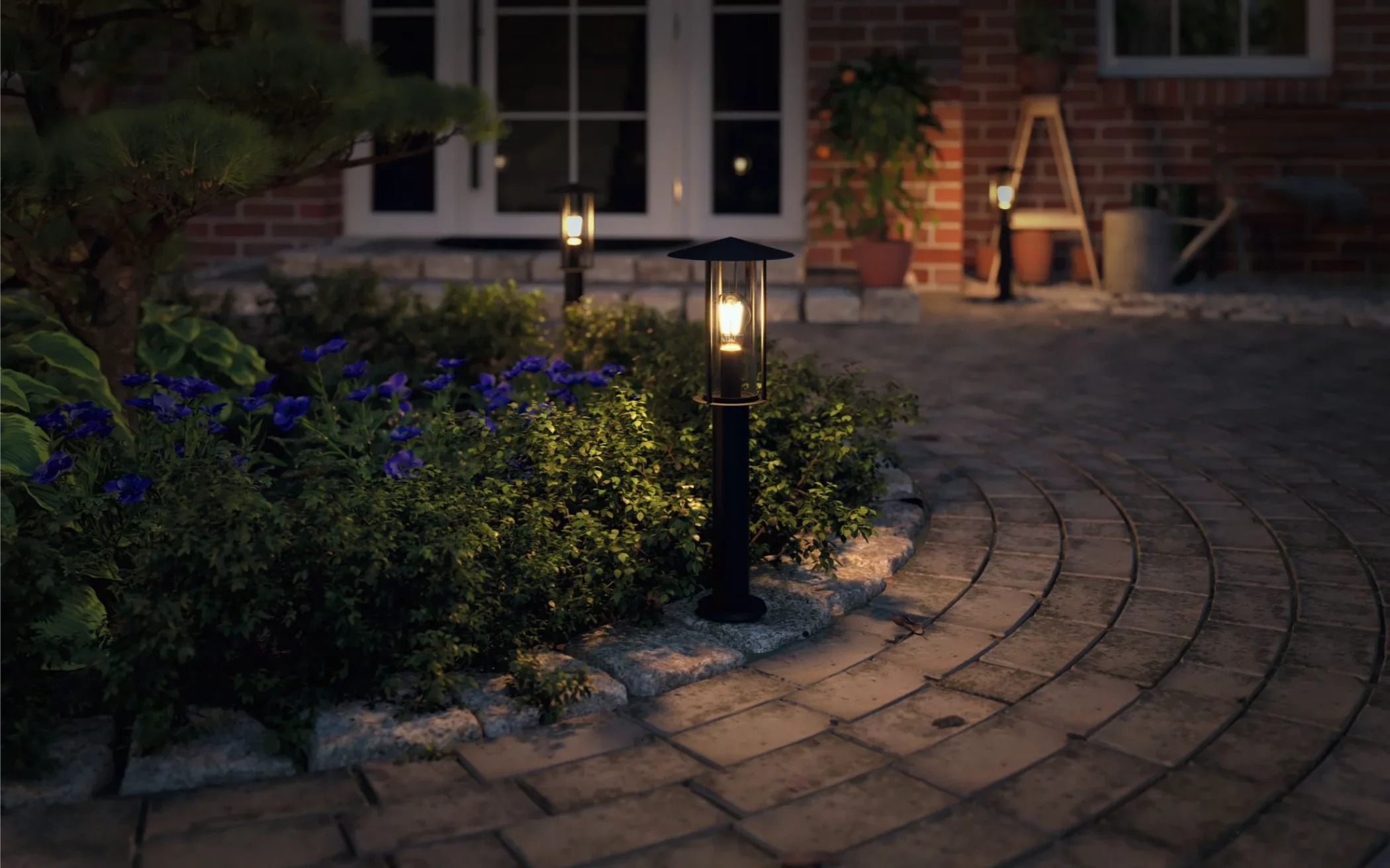 Abendlicher Gartenweg mit modernen Solarleuchten Garten zwischen Blumenbeeten und Pflastersteinen